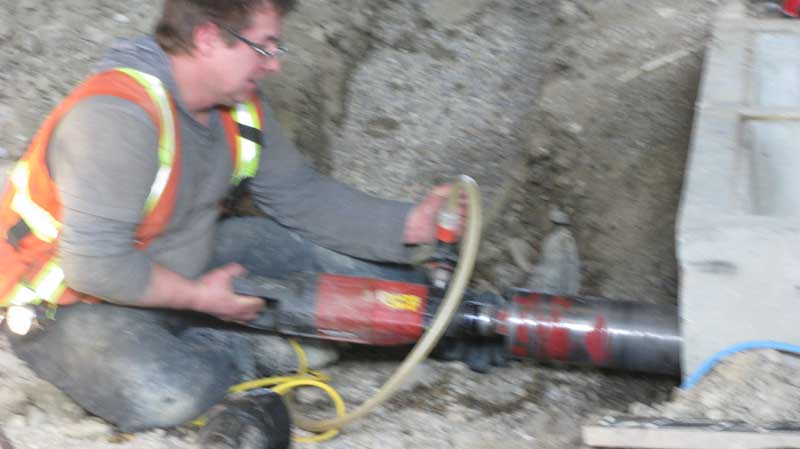 Photo of Murdo drilling rock for a underground containment system installed by Tryangle Mechanical